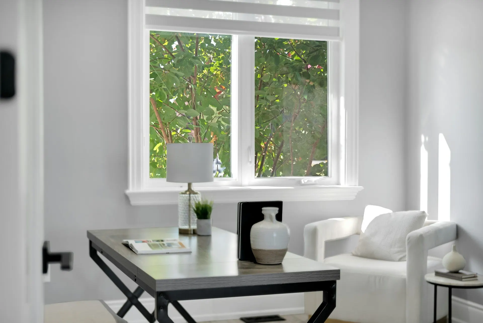 A bright home office with a desk by a window looking onto green trees