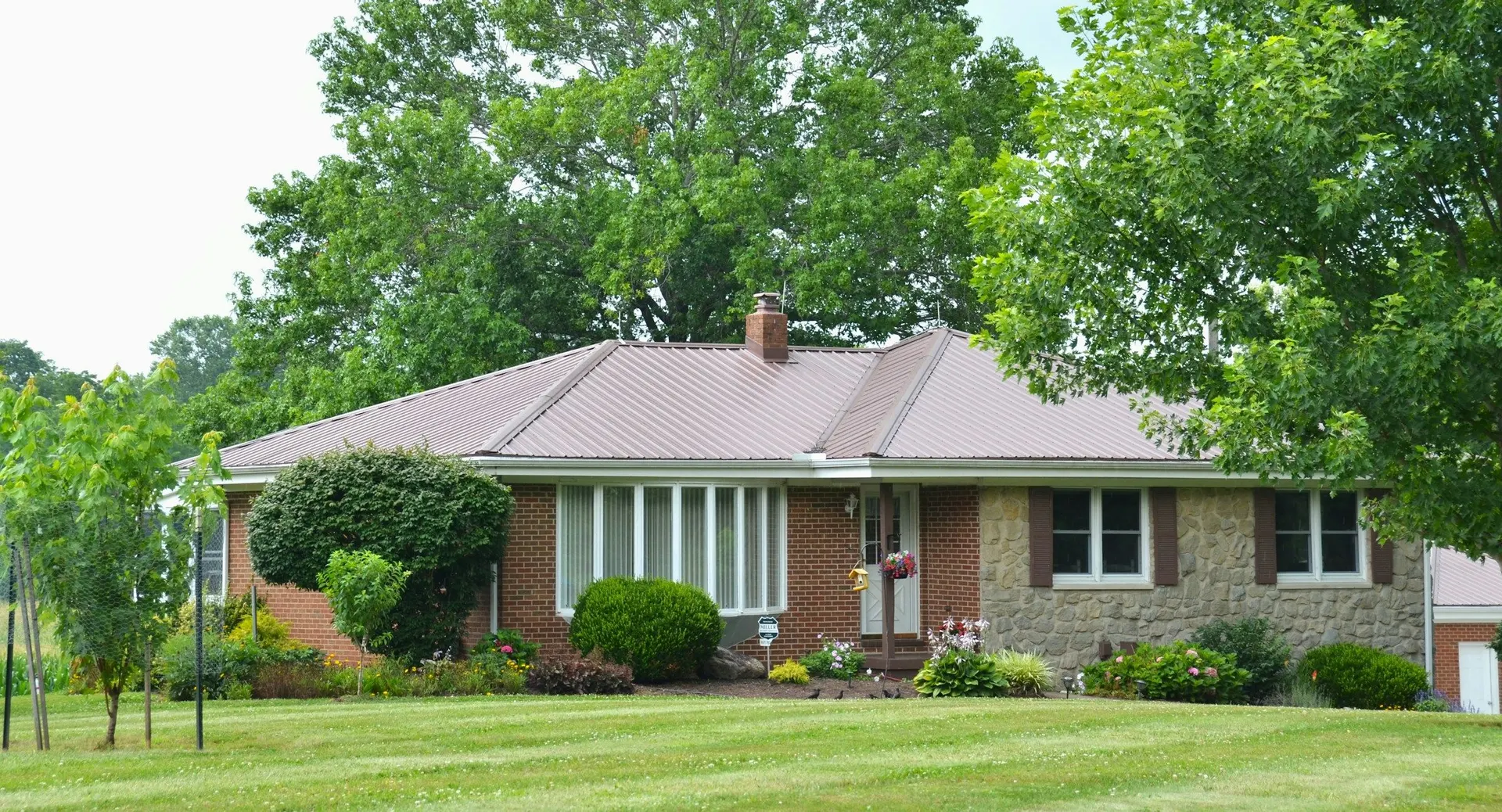 A well-kept brick and stone bungalow with a deep green lawn