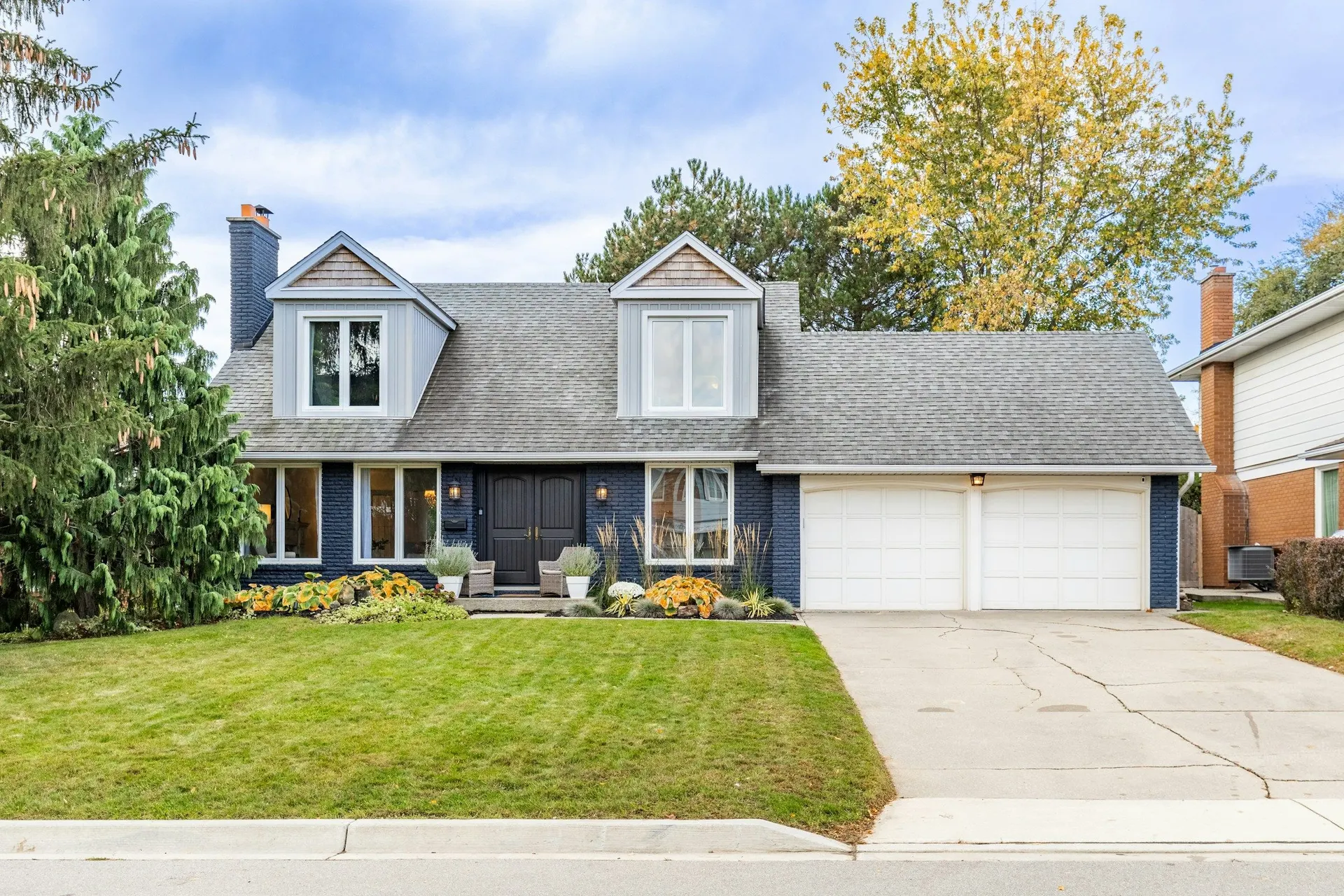 A suburban home with a double garage on a tidy street in autumn